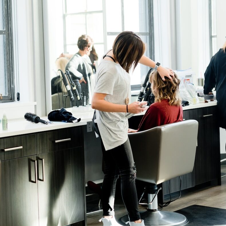 woman in gray sweater and black pants standing in front of mirror