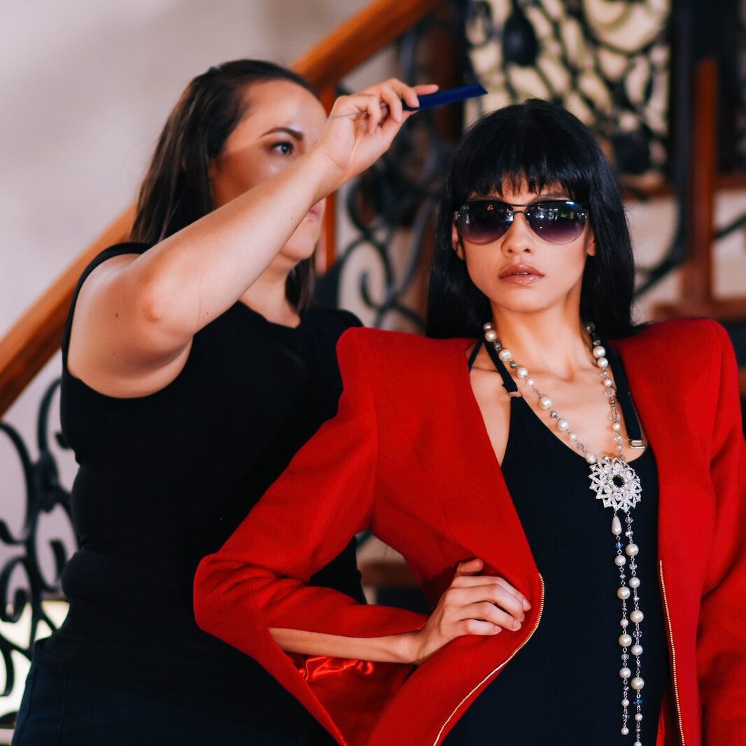 woman about to comb the hair of woman wearing red blazer